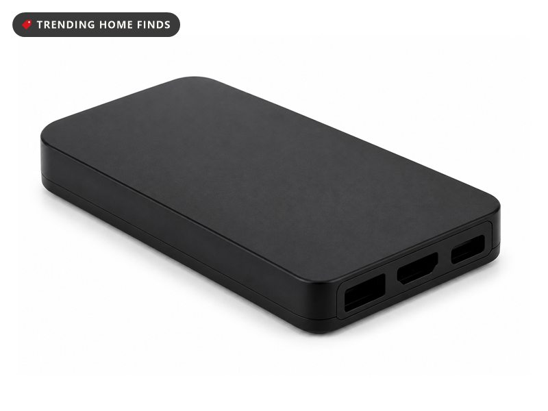 A small flat black capture card with rounded edges and plain ports along one short end.