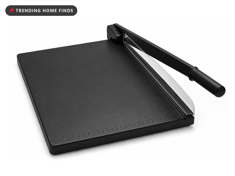 A black guillotine paper trimmer with a ruled edge, a long cutting arm and a clear safety guard.