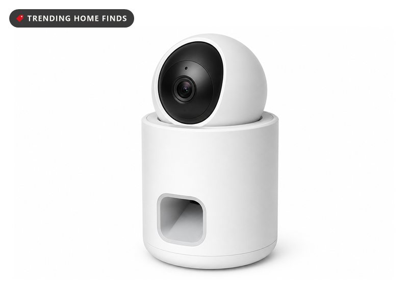 A small white pet camera with a round camera lens on top and a treat chute on the front.