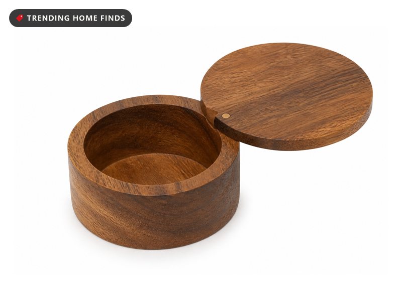 A round natural acacia wood salt cellar with its round wooden lid swung open on a pivot.