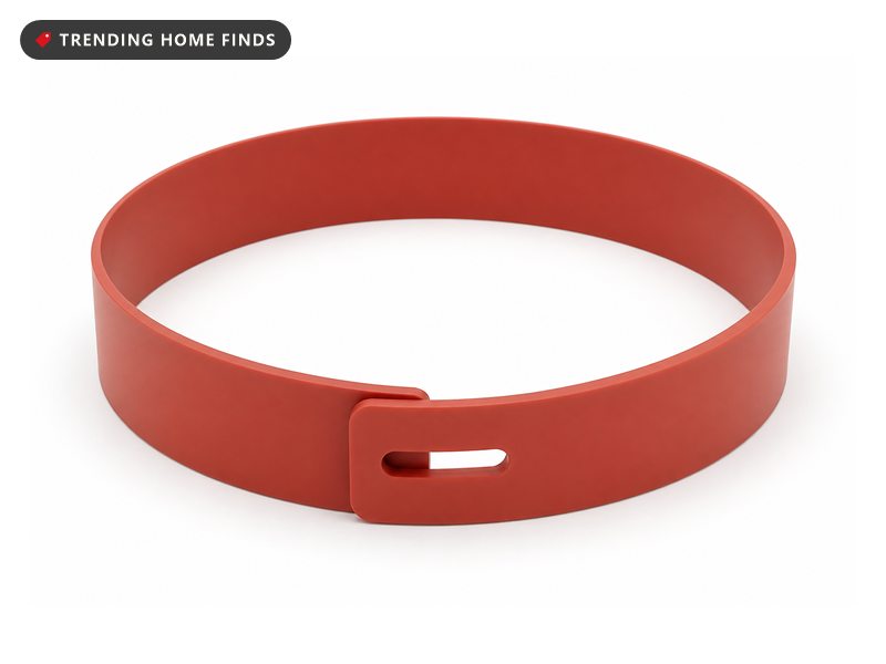 A flat terracotta red silicone pie crust shield ring with a slotted tab to set its size.