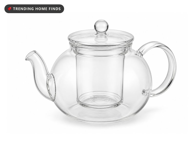 A round clear borosilicate glass teapot with a curved spout, a glass handle, a clear lid and a glass infuser inside.