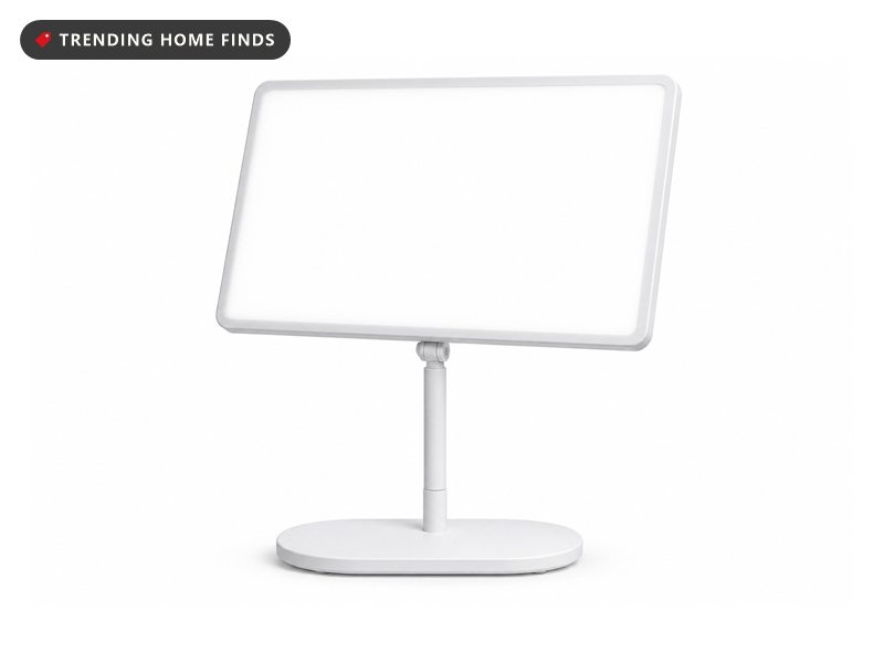 A white light therapy lamp with a large glowing panel on a slim adjustable pole and oval base.