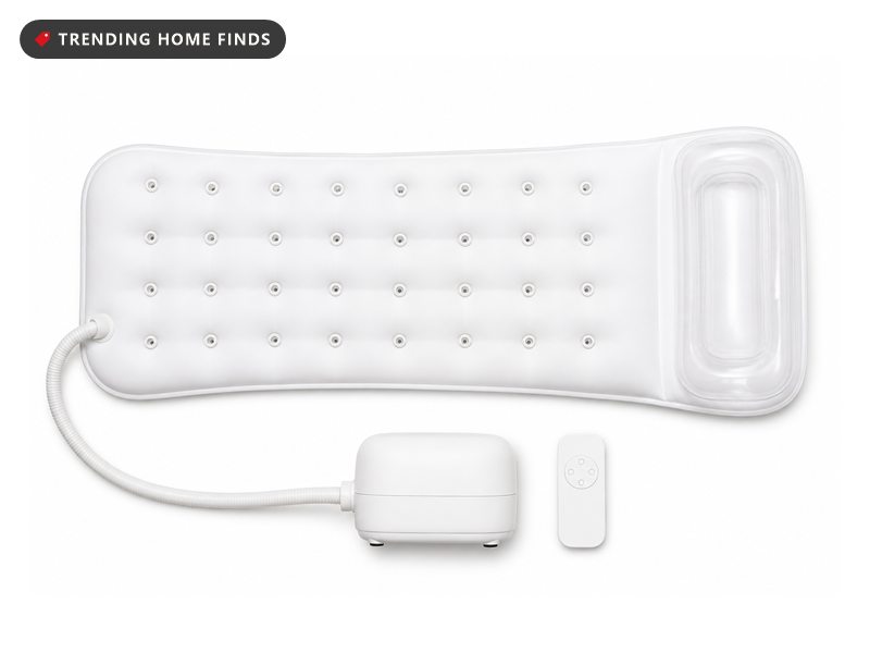 A long white bubble bath mat with rows of jet holes, a clear inflatable pillow at one end and a hose to a small pump unit.