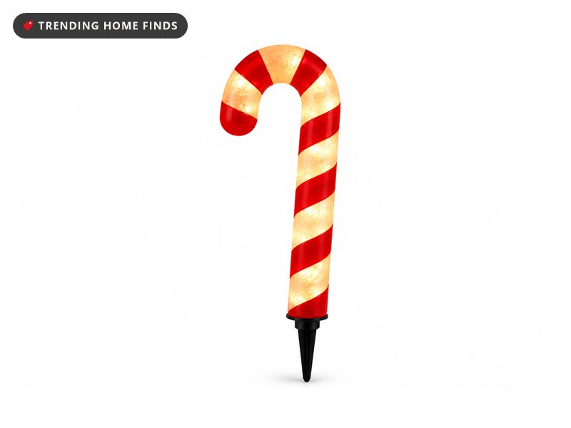 A lighted red and white candy cane on a black ground stake, glowing from inside.