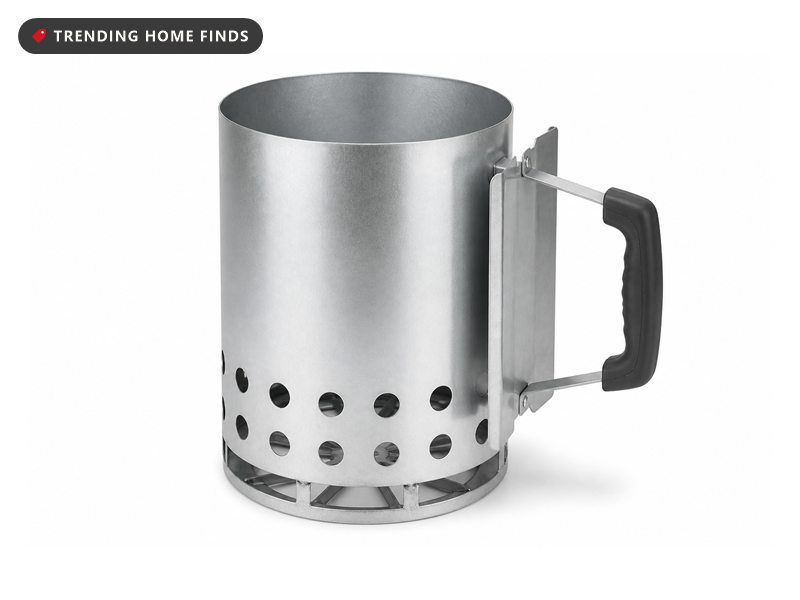 A tall round aluminized steel chimney starter with rows of vent holes, a cone shaped bottom grate and a side handle.