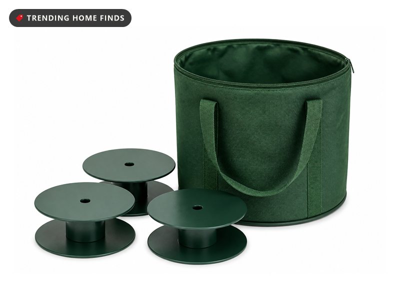 A green zip storage bag with stitched handles standing open beside three round metal light reels.