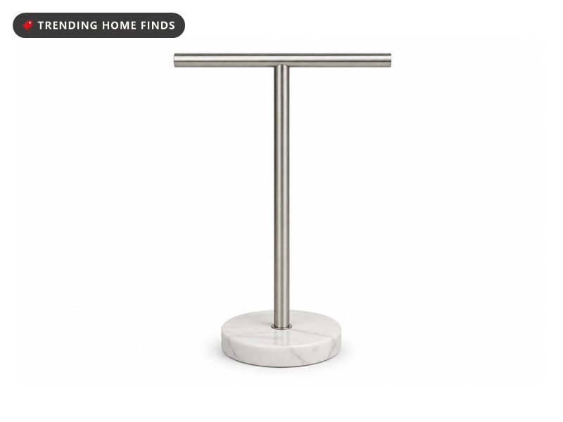 A brushed stainless steel T shaped hand towel stand on a small round white marble base.