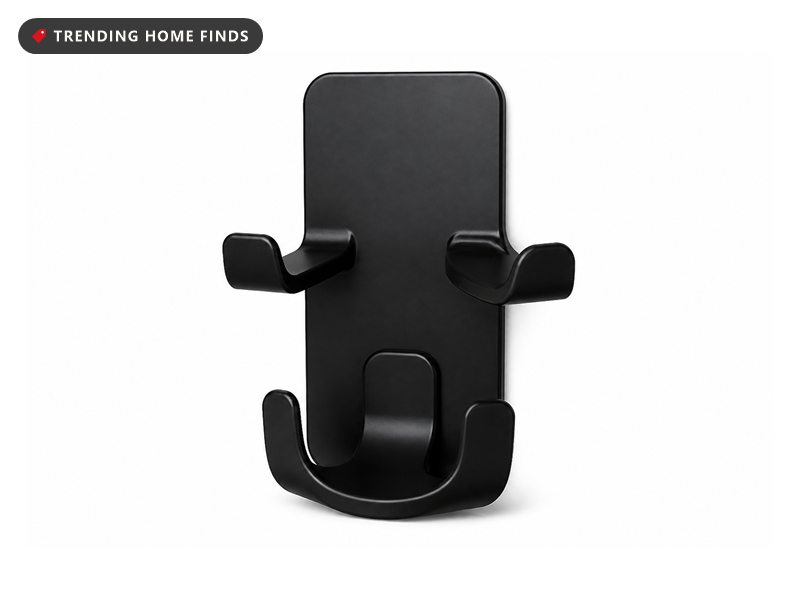 A slim black wall holder with two curved arms for controllers and a hook for a headset.
