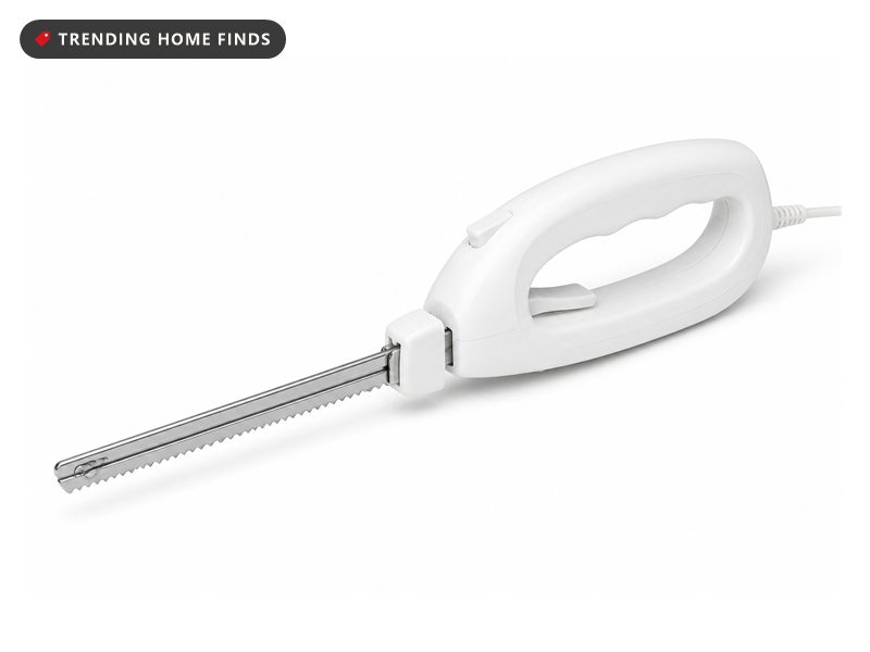 A white handled electric carving knife with twin serrated stainless steel blades and a trailing cord.