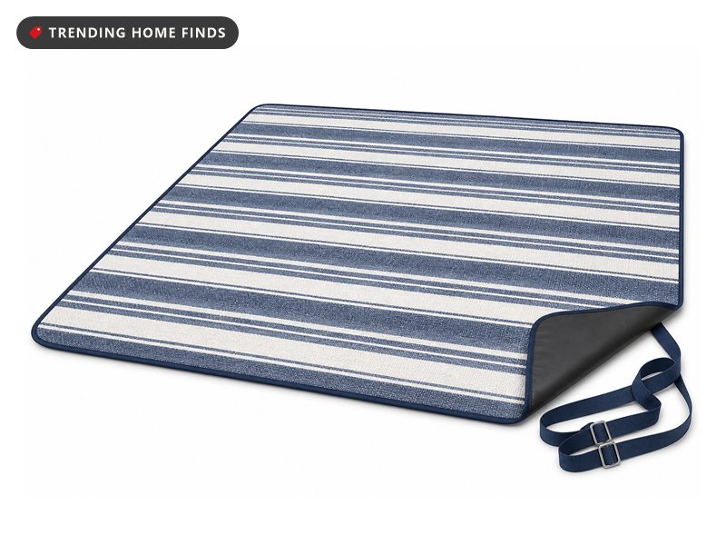 A large blue and white striped picnic blanket spread flat with one corner turned back to show the waterproof backing.