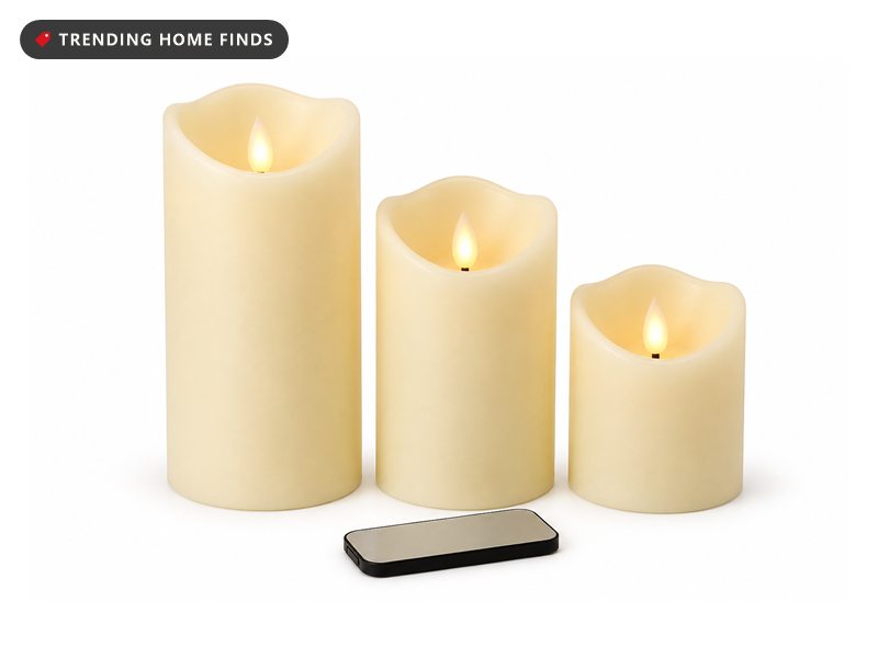 Three ivory real wax pillar candles of stepped heights with glowing LED flames and a small remote in front.