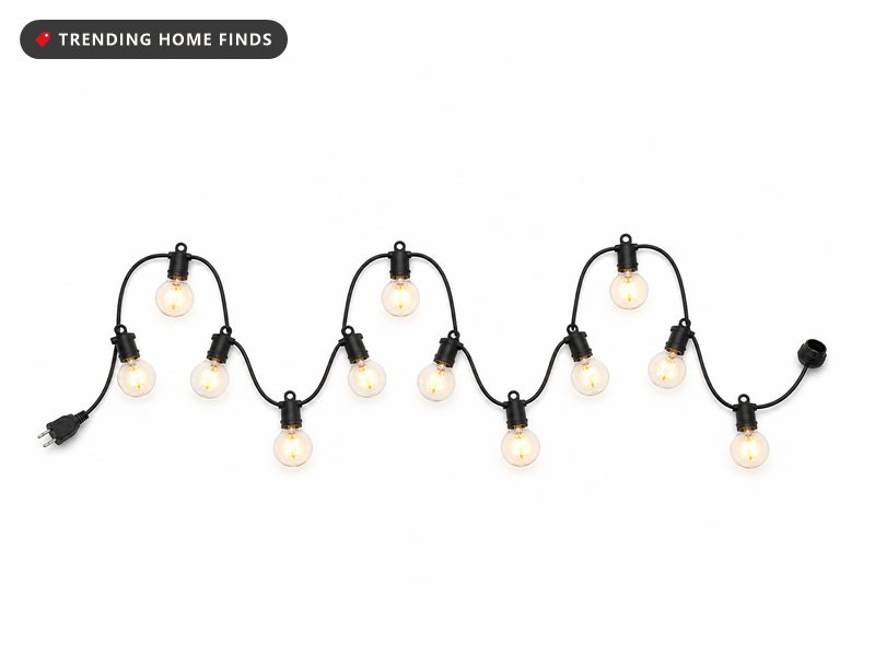 A black cord strand of round clear globe bulbs glowing warm white, laid in a gentle wave.