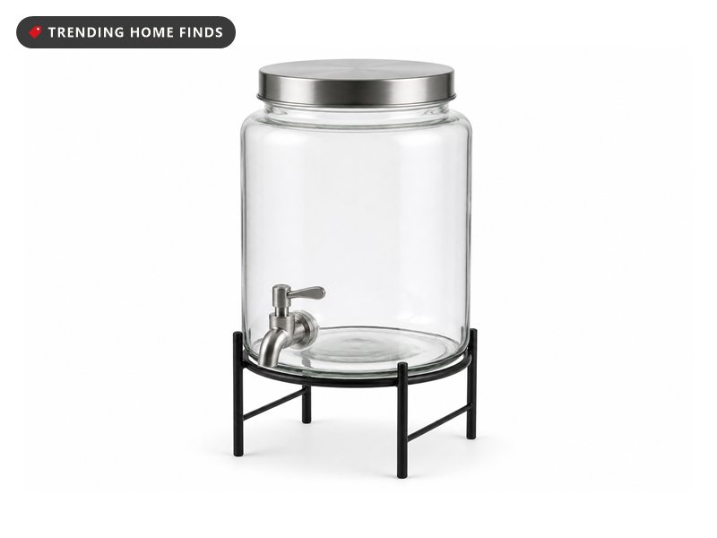A 2 gallon glass beverage dispenser with a lid and a stainless spigot, set on a black metal stand.