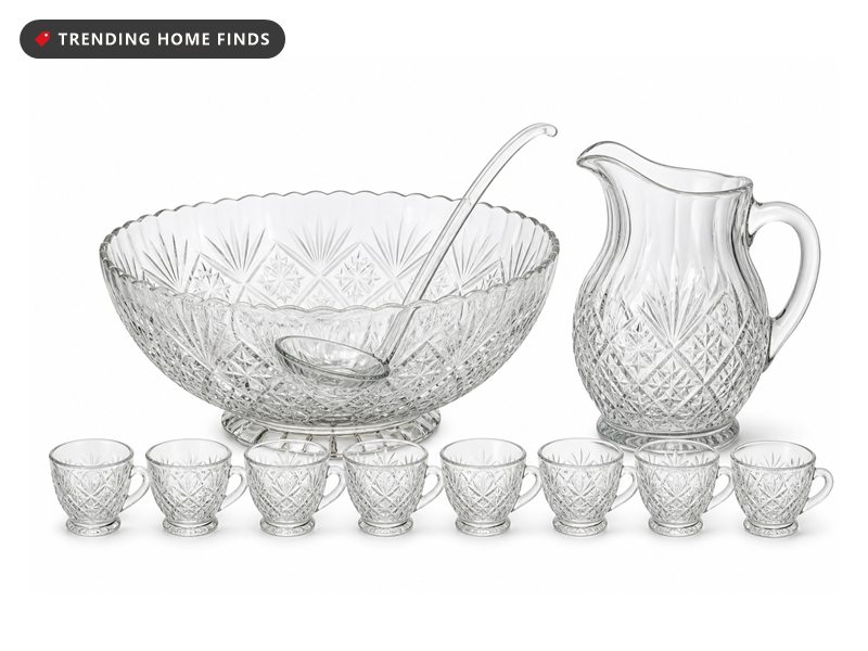 A clear glass punch bowl with a glass ladle, a glass pitcher beside it and eight small clear cups in a row.