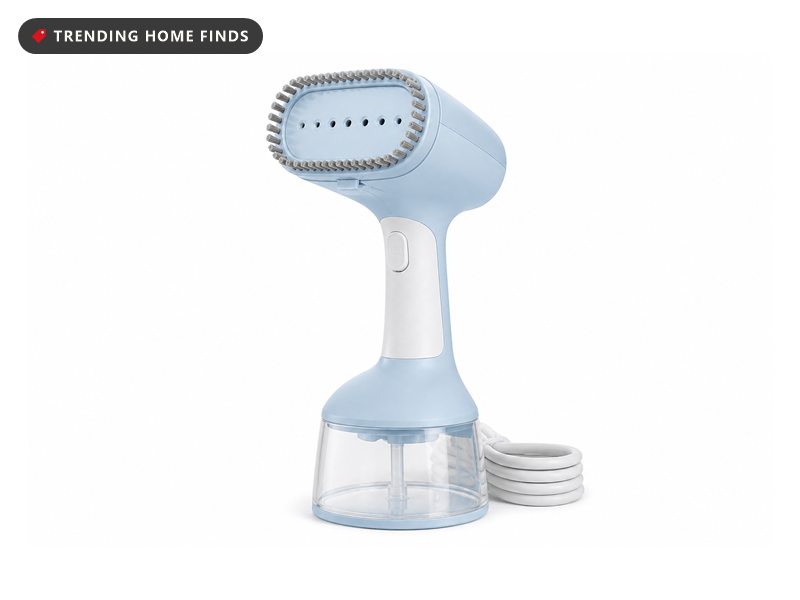 A pale blue and white handheld garment steamer with a clear water tank and a fabric brush on the steam head.