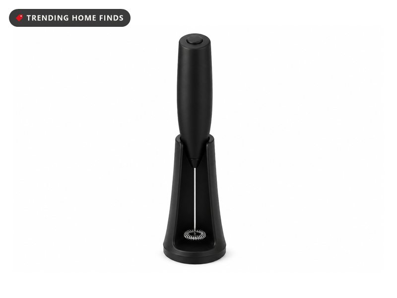 A black handheld milk frother with a steel shaft and coil whisk standing in its upright stand.