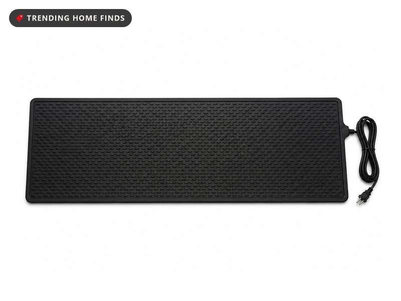 A long narrow black rubber heated snow melting mat with a no slip texture and a power cord.