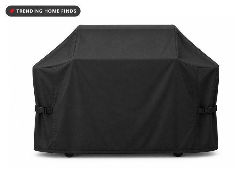 A black heavy duty grill cover shaped over a gas grill with side straps.