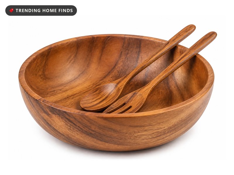 A large round acacia wood salad bowl with a matching wooden spoon and fork inside.