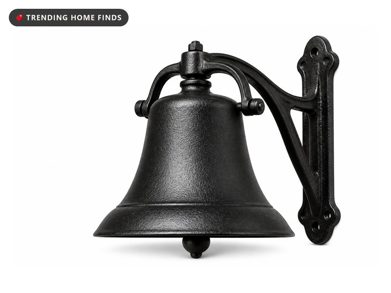 A large black cast iron farmhouse dinner bell hanging from a curved wall bracket.