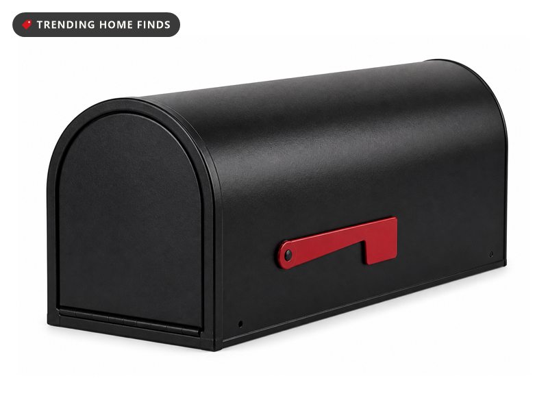 A large black steel curbside mailbox with a rounded top, a front door and a red side flag.