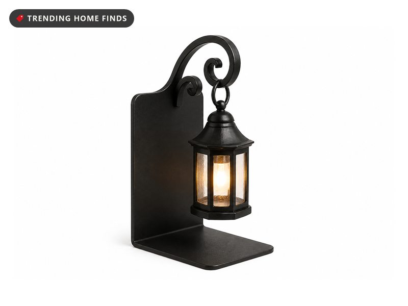An antique black library lantern bookend with a scroll bracket and a glowing mini lantern.