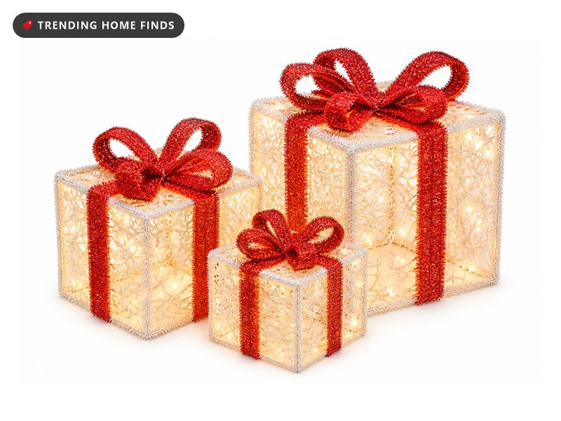 Three tinsel wrapped lighted gift boxes with red bows glowing warm white.