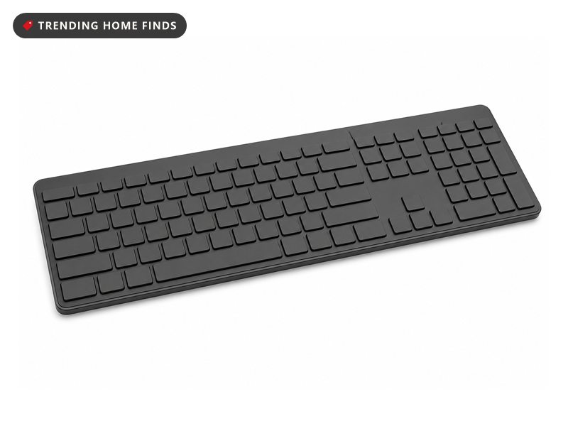 A slim graphite full size keyboard with low blank keys and a number pad, seen from a front three quarter angle.