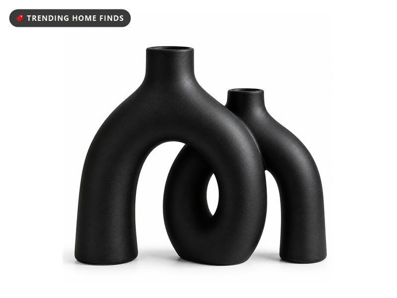 Two matte black ceramic vases with hollow looping arch shapes, leaning together as a pair