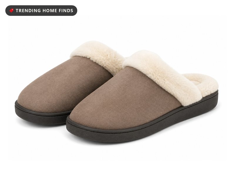 A pair of taupe faux suede slip on house slippers with a fluffy cream plush lining and a dark rubber sole.