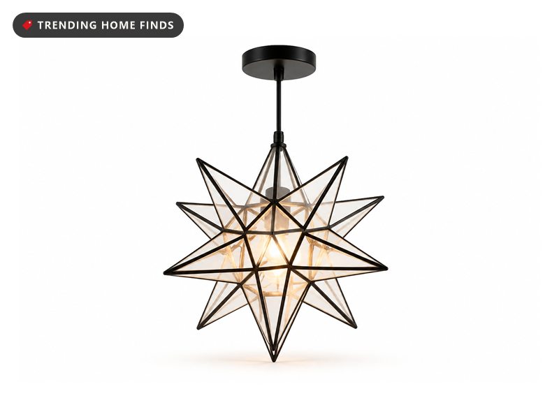 A clear glass Moravian star pendant light hanging from a black cord, glowing warm.