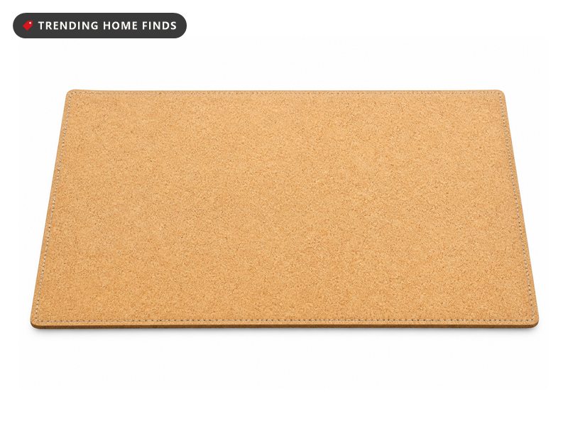 A large rectangular natural cork desk mat with a speckled grain and a stitched border, seen from a low angle.