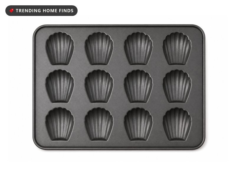 A dark gray nonstick madeleine pan pressed with twelve shallow scallop shell cavities.