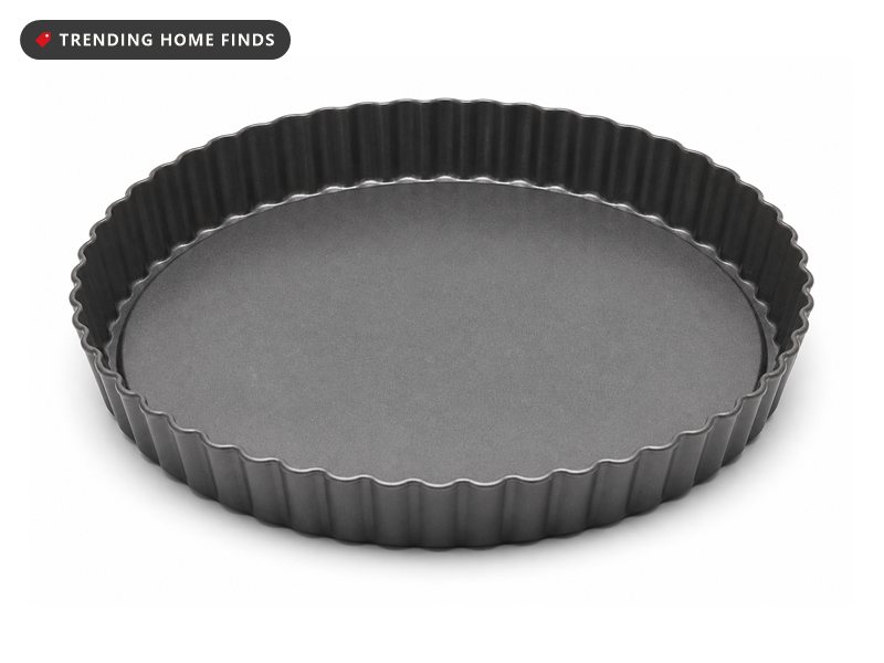 A dark gray nonstick fluted tart pan with a removable flat base seated inside the ring.