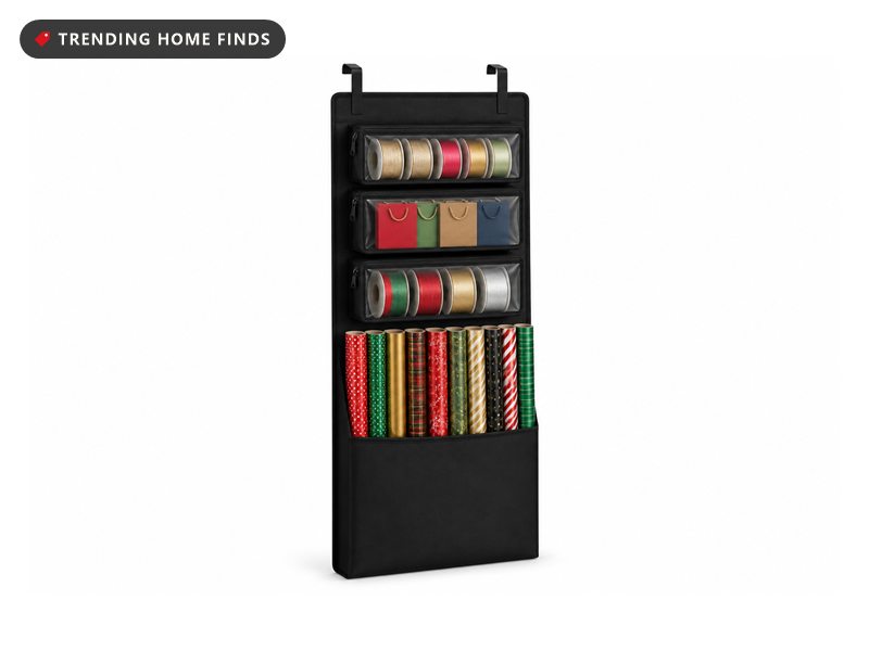 A long black fabric gift wrap organizer with over door hooks, an open roll sleeve and removable zip bins.