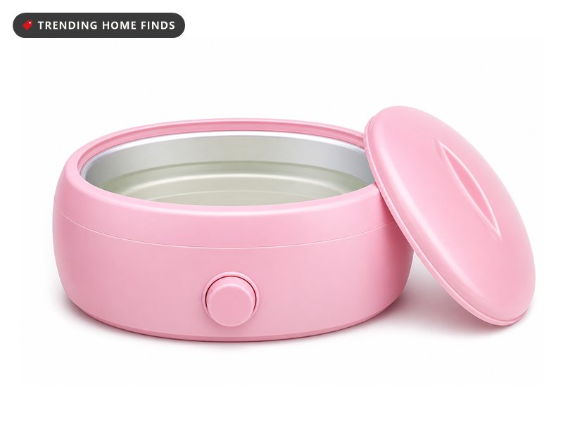 A compact pink paraffin wax bath warmer with melted wax inside and its lid set beside it.