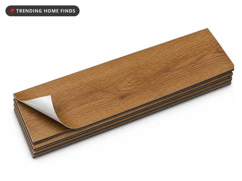 A small stack of wood look vinyl floor planks, the top plank's corner lifted to show its backing.