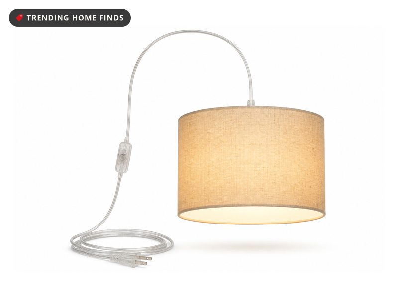 A plug in pendant with a beige linen drum shade glowing warm, a long clear cord, an inline switch and a US plug.