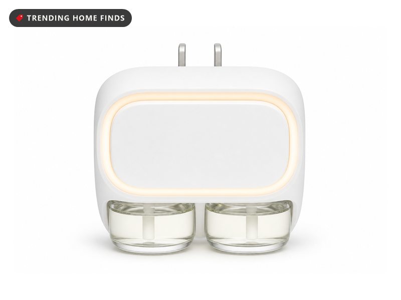 A small white plug in fragrance diffuser with two glass scent vials in its underside and a glowing ring on its face.