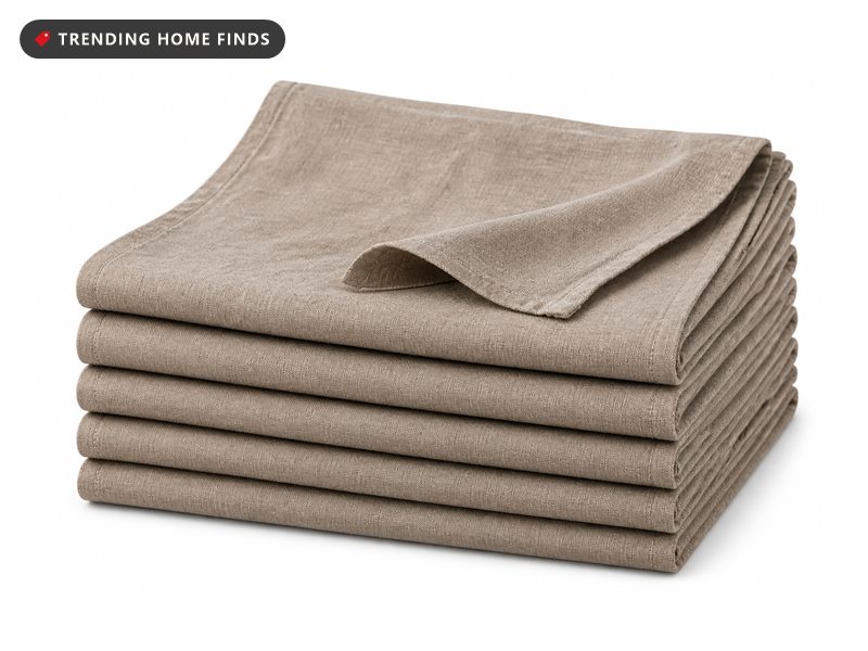 Six taupe gray linen dinner napkins, folded and stacked with the top one loosely draped.