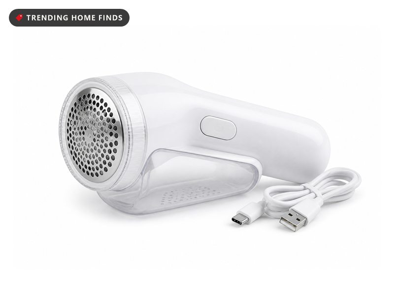 A compact white fabric shaver with a clear round lint chamber and a round mesh guard at its head.