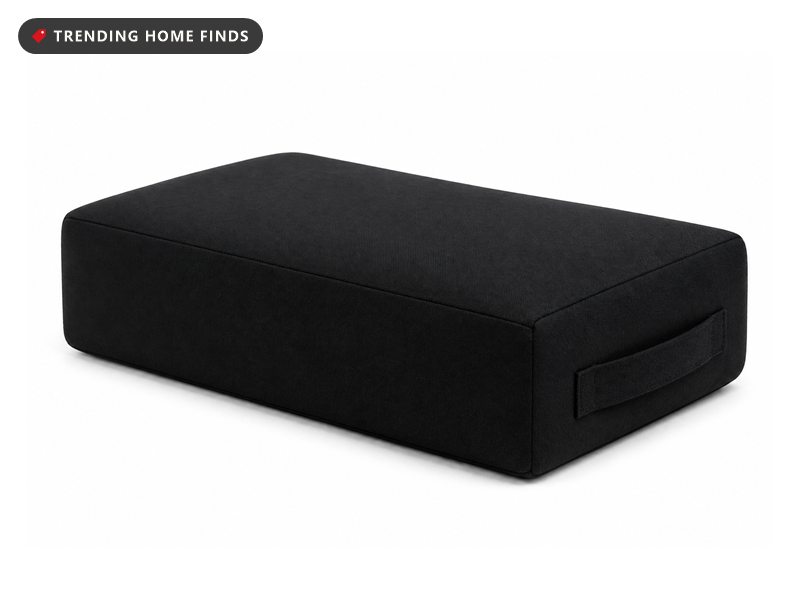 A firm rectangular black cotton yoga bolster with a flat top and a carry handle on one end.