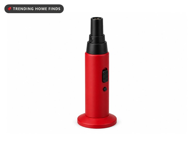 A compact red refillable butane torch standing upright on a flat base with a short black nozzle.