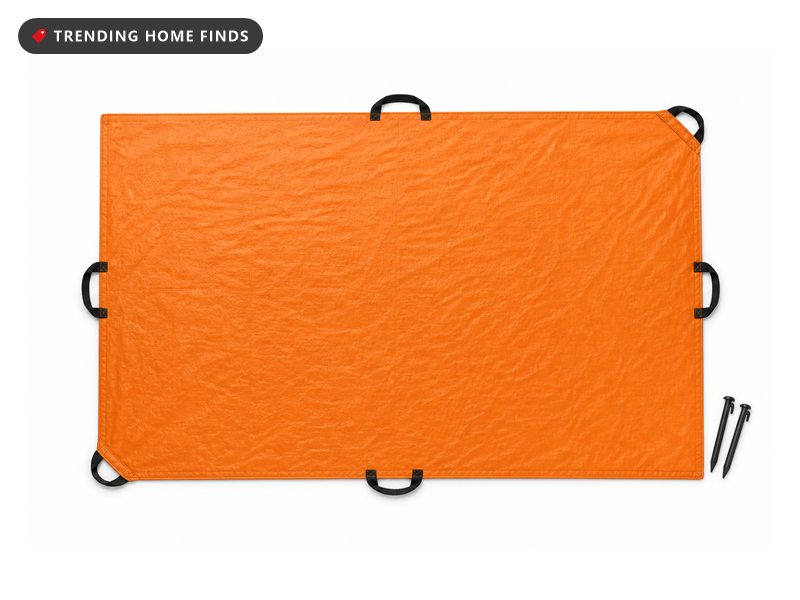 A rectangular orange leaf tarp with six black strap handles and two ground stakes.
