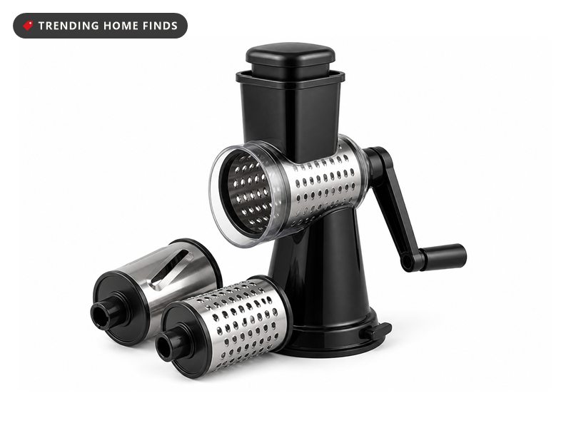 A black rotary cheese grater on a suction base with a hopper, a side drum and two spare drums.
