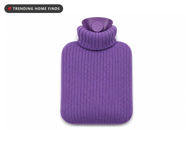 A purple rubber hot water bottle inside a soft ribbed knit cover.