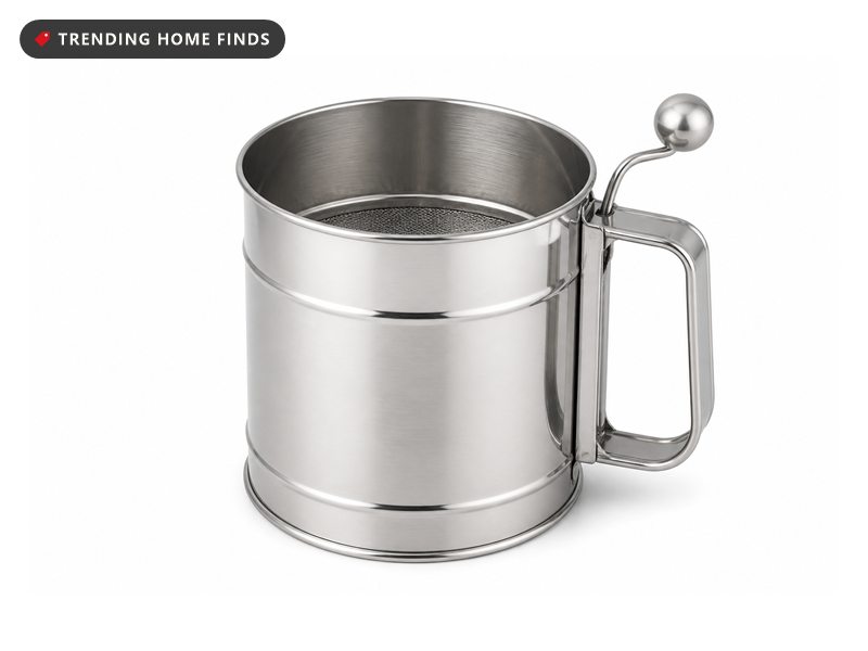 A tall silver stainless steel flour sifter with a side handle and a small hand crank.
