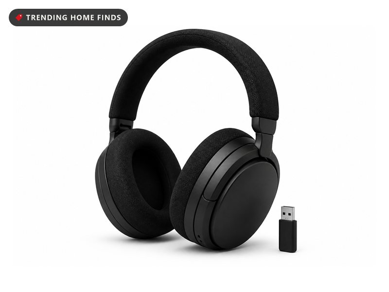 A black over ear wireless gaming headset with a fabric headband and a retracted boom microphone, a small USB dongle beside it.