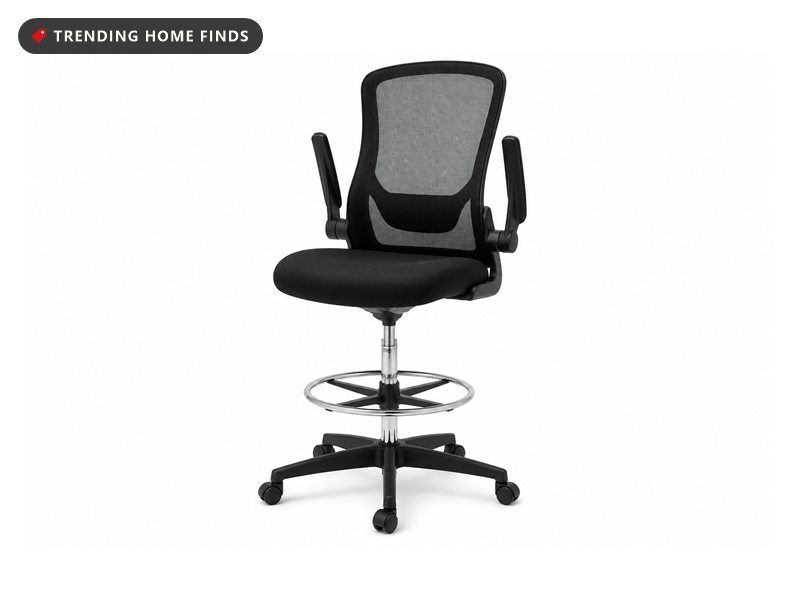 A tall black mesh drafting chair with a chrome foot ring, flip up arms and a five caster base.
